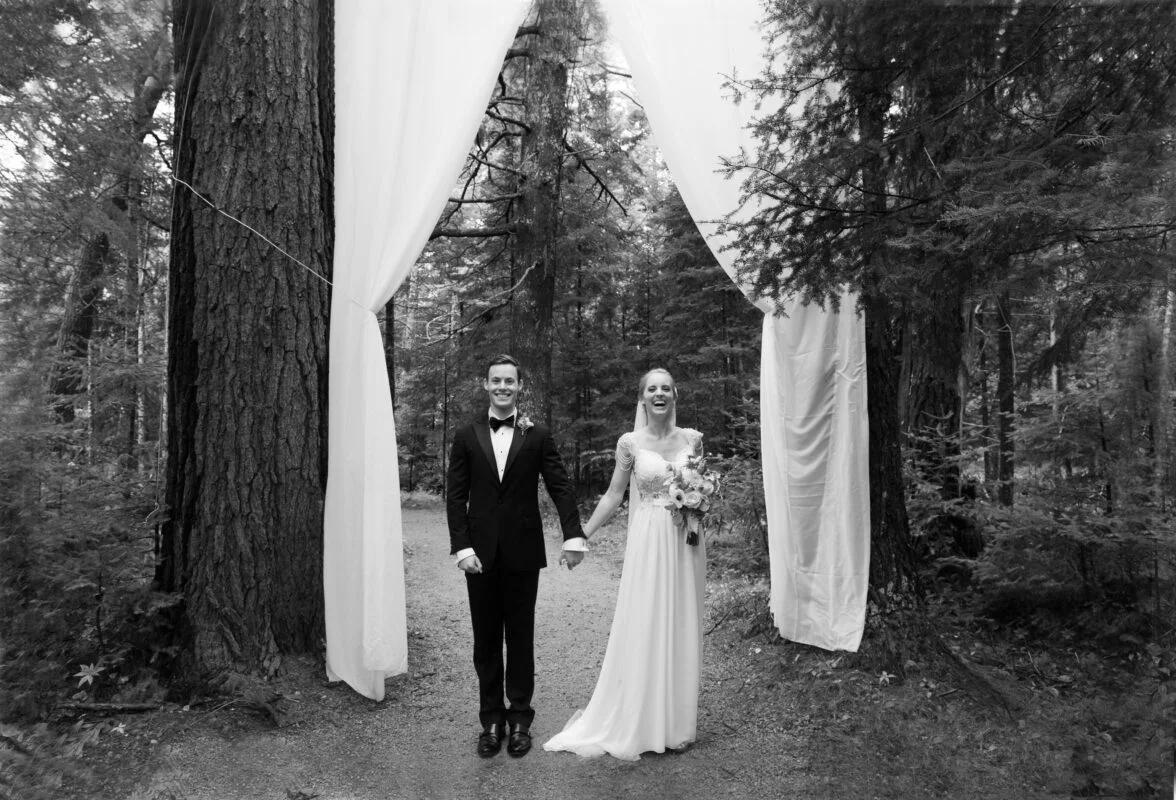 A bride and groom standing in the woods.