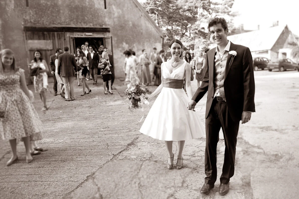 A bride and groom walking in front of a barn.