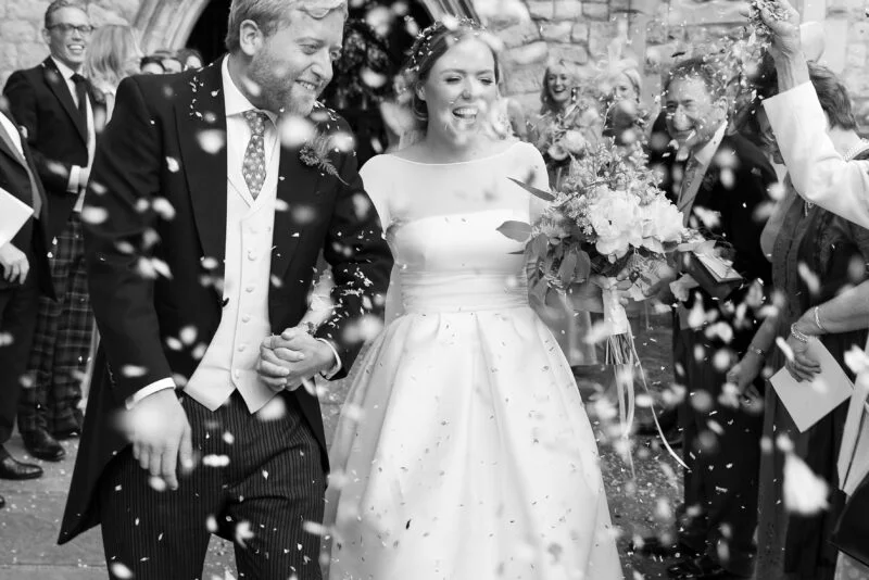 A bride and groom are surrounded by confetti at their wedding.