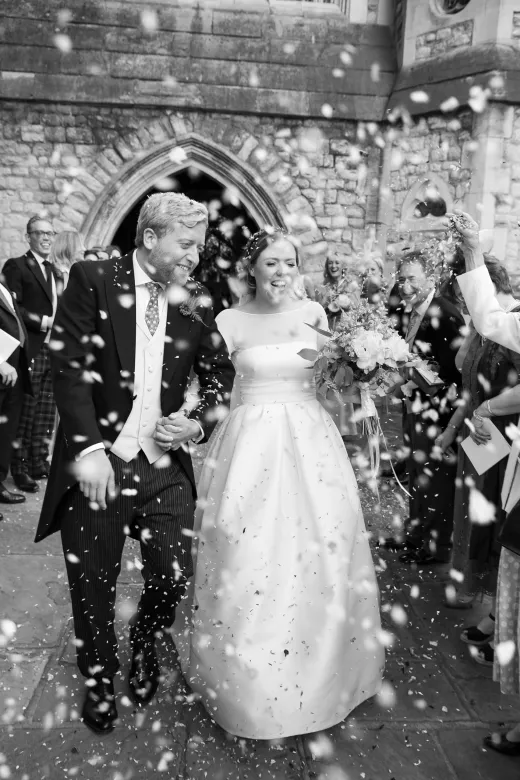 A bride and groom are surrounded by confetti at their wedding.