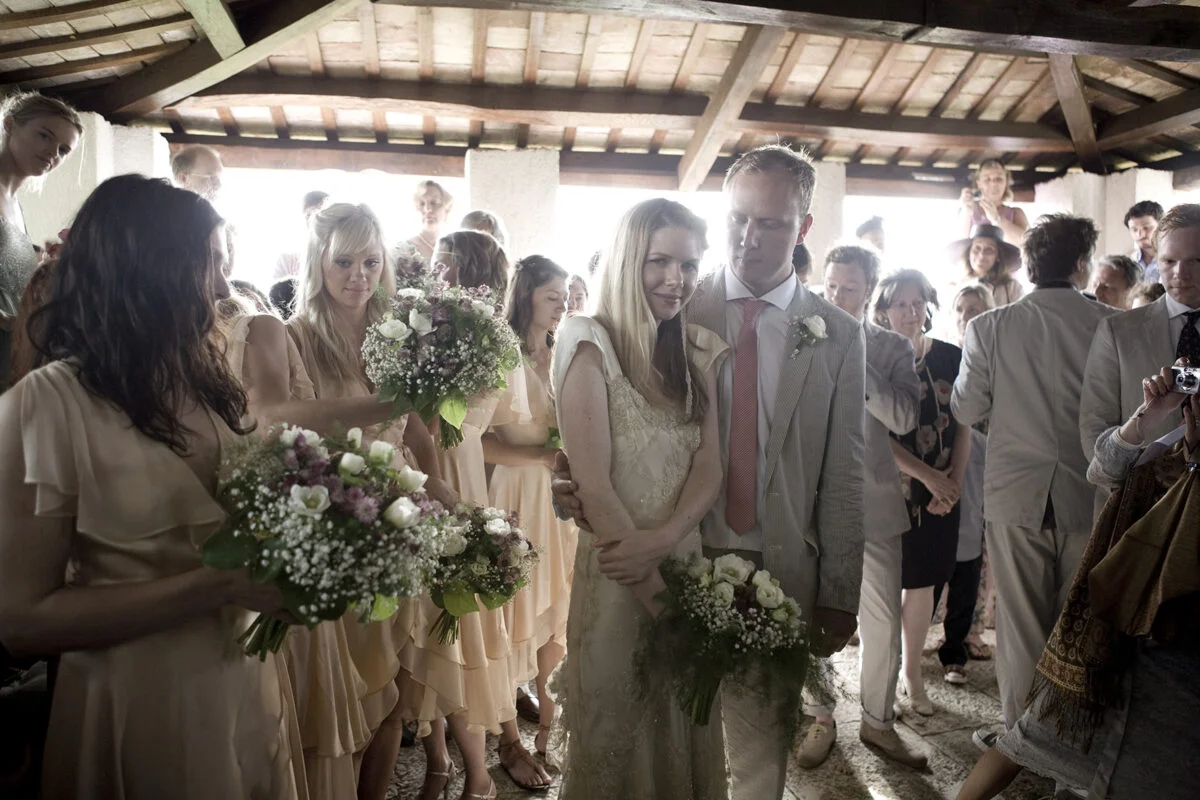 A bride and groom walk down the aisle with their bouquets.