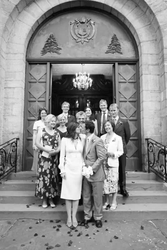 A black and white photo of a wedding party in front of a church.