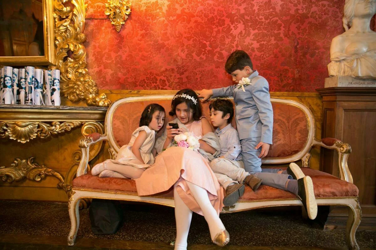 A group of children sitting on a couch in an ornate room.