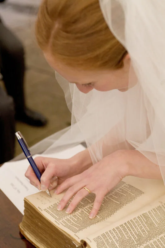 A woman wearing a veil writing in a book.