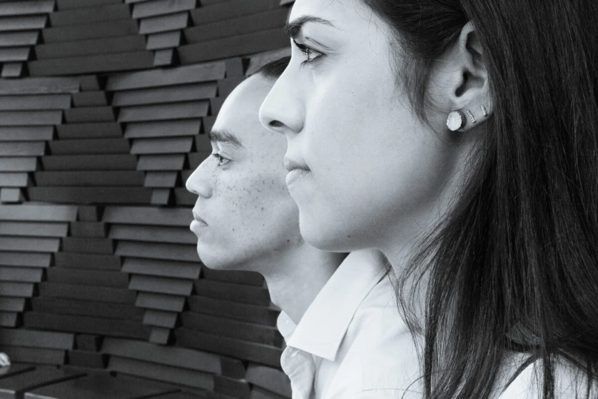 Black and white photo of a man and woman in front of a wall.