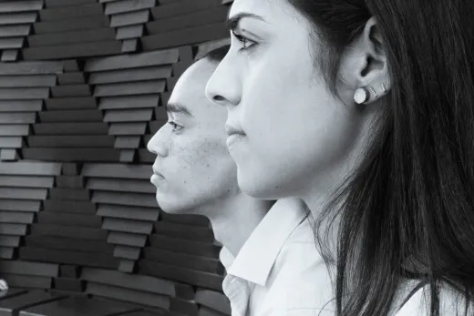 Black and white photo of a man and woman in front of a wall.