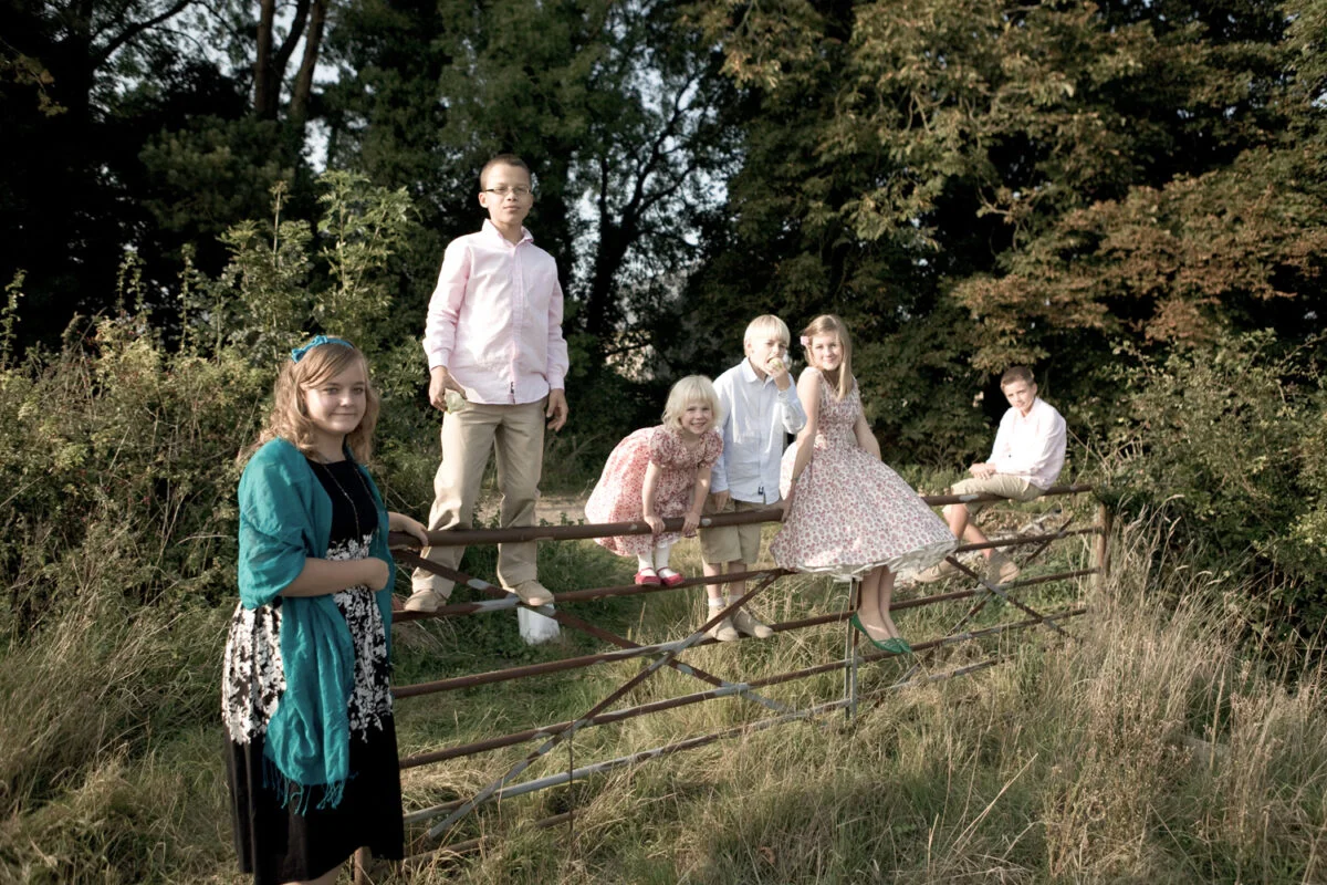 A group of people standing on a fence in a field.