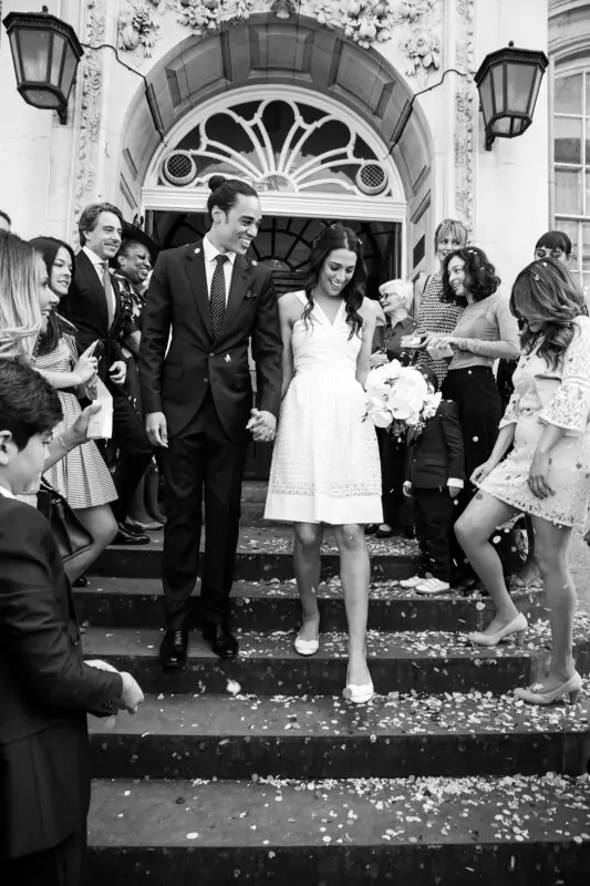 A bride and groom walking down the steps of a building.
