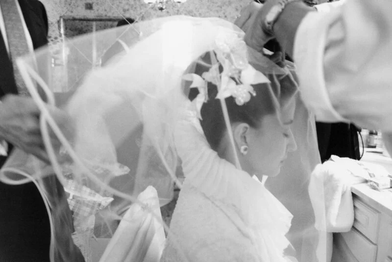 A bride getting her veil on in front of a mirror.