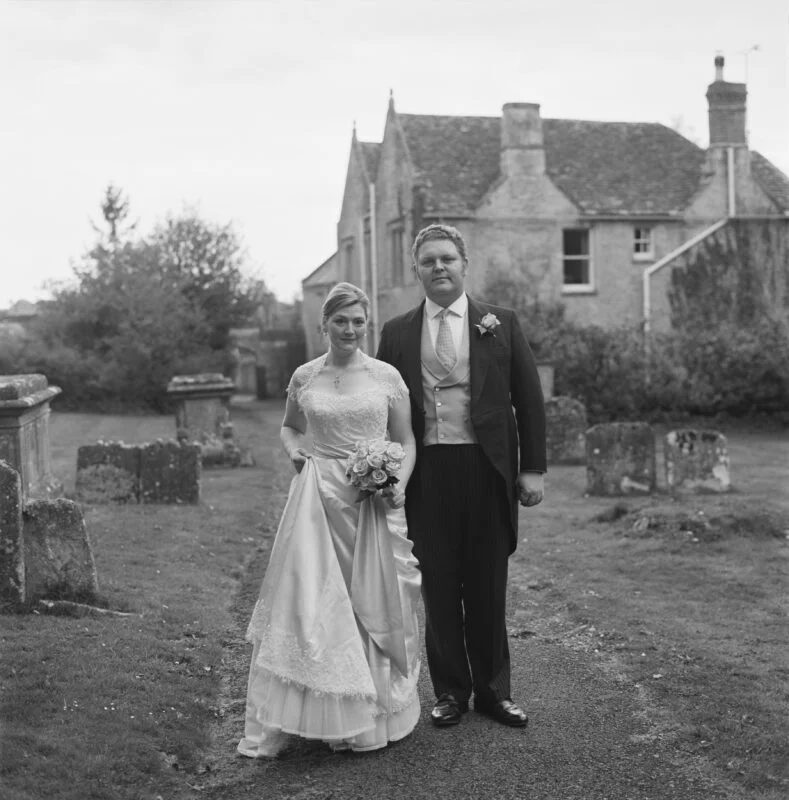 A bride and groom standing in front of a graveyard.