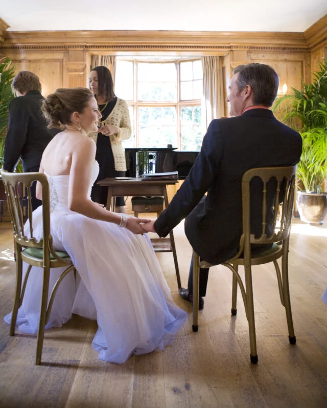 A bride and groom sitting in chairs.