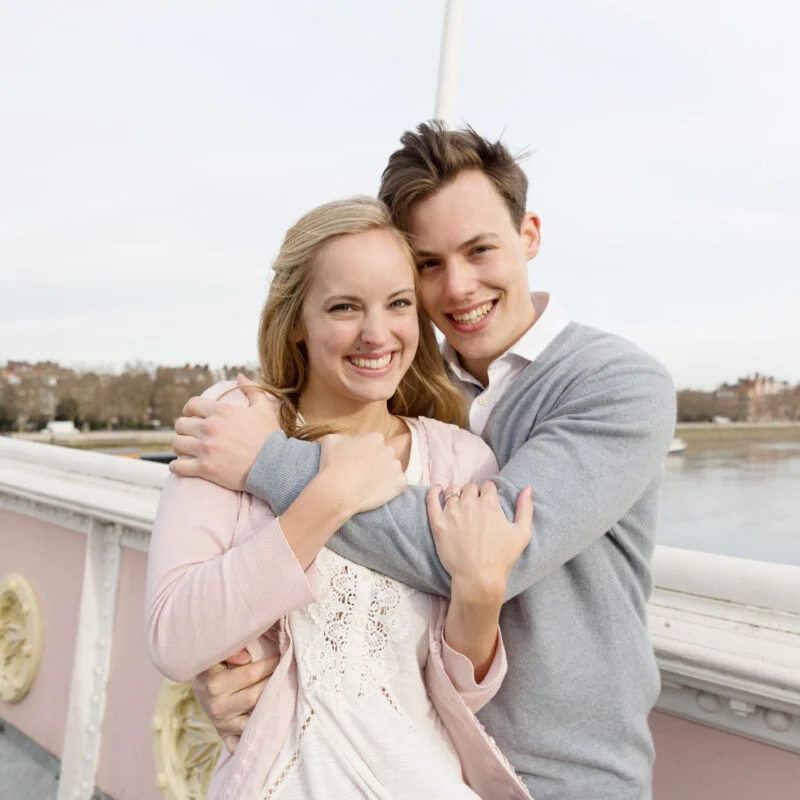 A man and a woman hugging on a bridge.