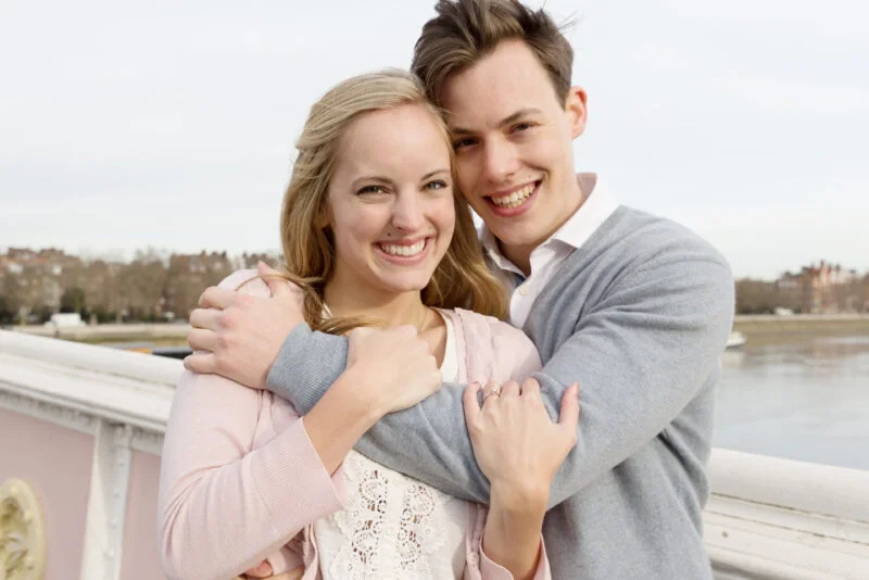 A man and a woman hugging on a bridge.