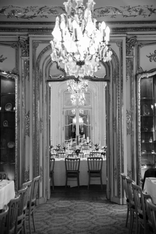 A black and white photo of an ornate dining room.