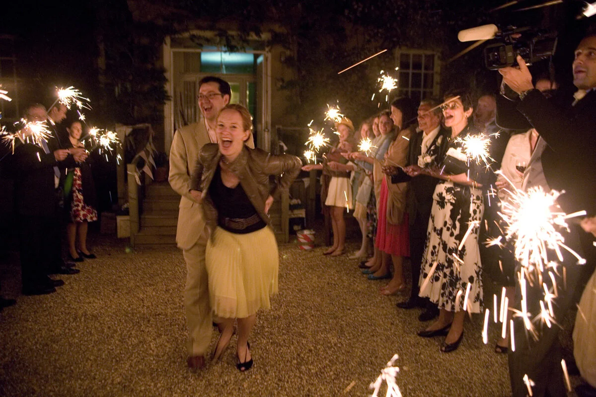 A man and woman holding sparklers in front of a crowd.