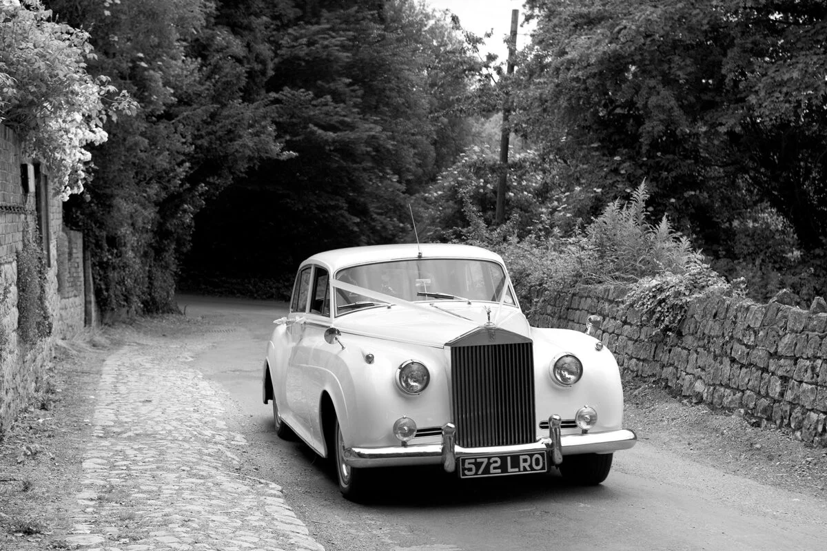A black and white photo of a rolls royce wedding car.