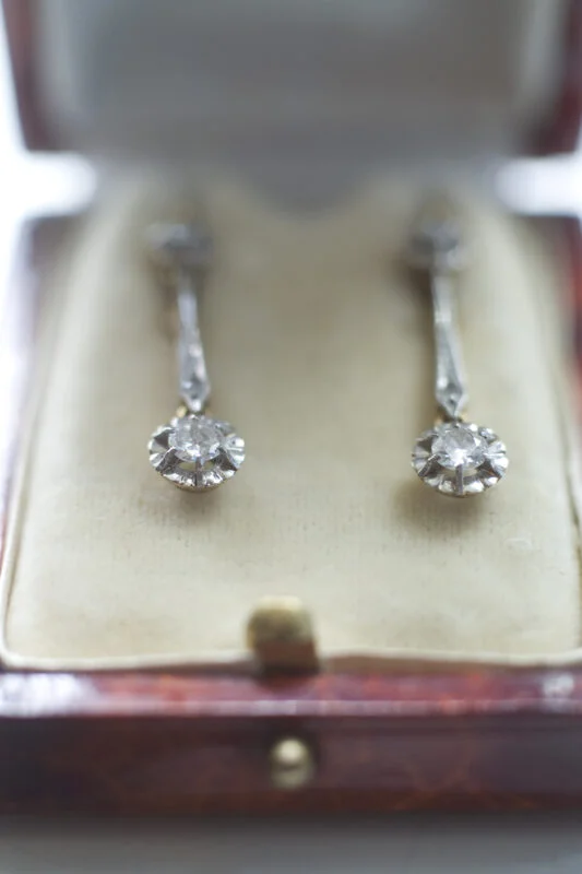 A pair of diamond earrings in a wooden box.