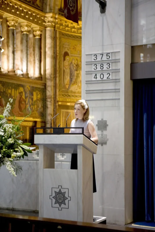 A woman standing at a podium in front of a church.