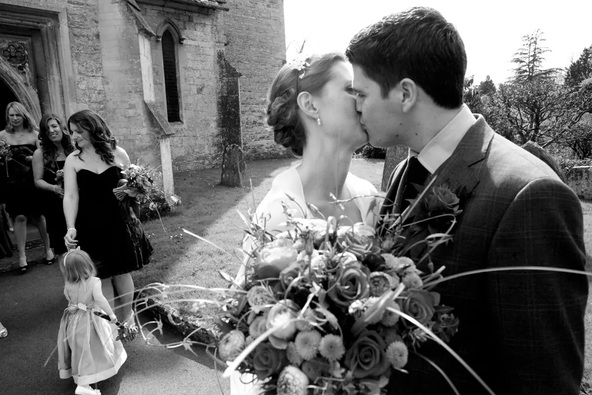 A bride and groom kiss in front of a church.