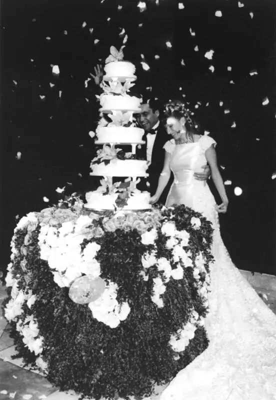 A bride and groom standing in front of a wedding cake.