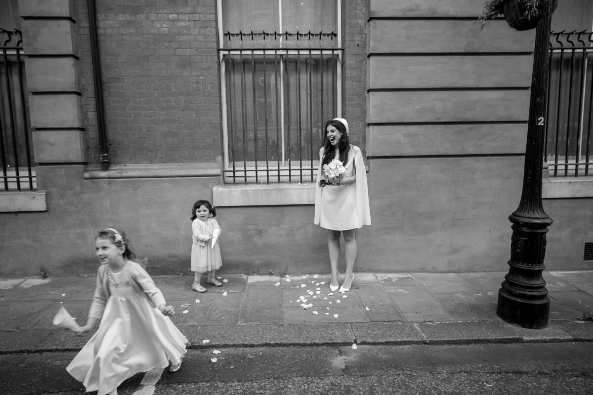 A black and white photo of a girl in a dress walking down the street.