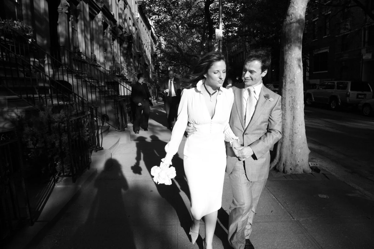 A black and white photo of a couple walking down the street.