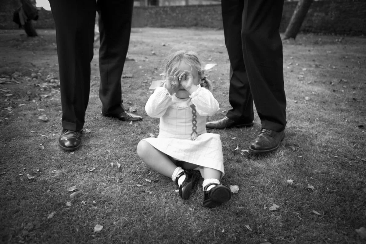 Black and white photo of a little girl sitting on the ground.