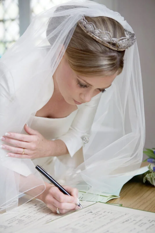A bride signing her wedding vows with a pen.