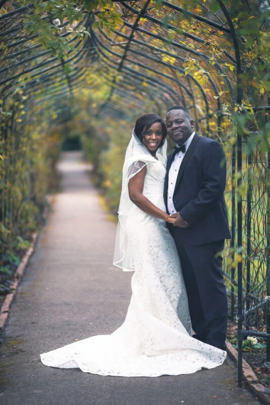 A bride and groom posing for a photo in a garden.