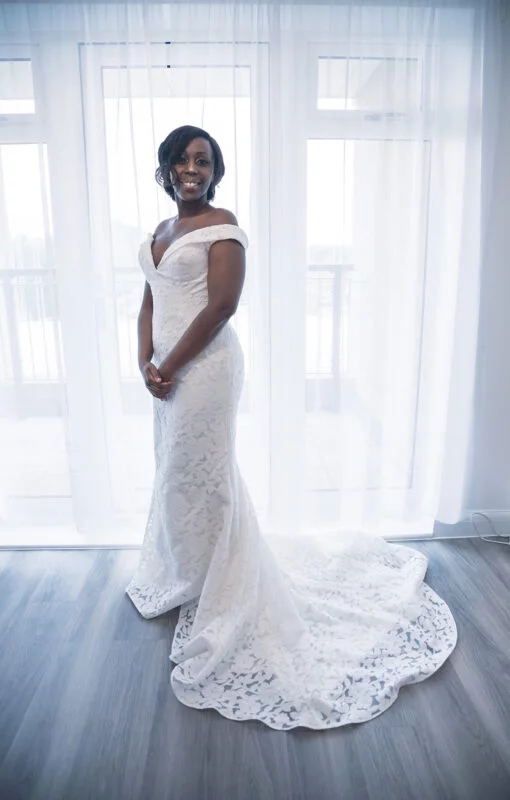 A woman in a wedding dress standing in front of a window.