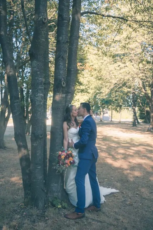 A bride and groom kissing under a tree.