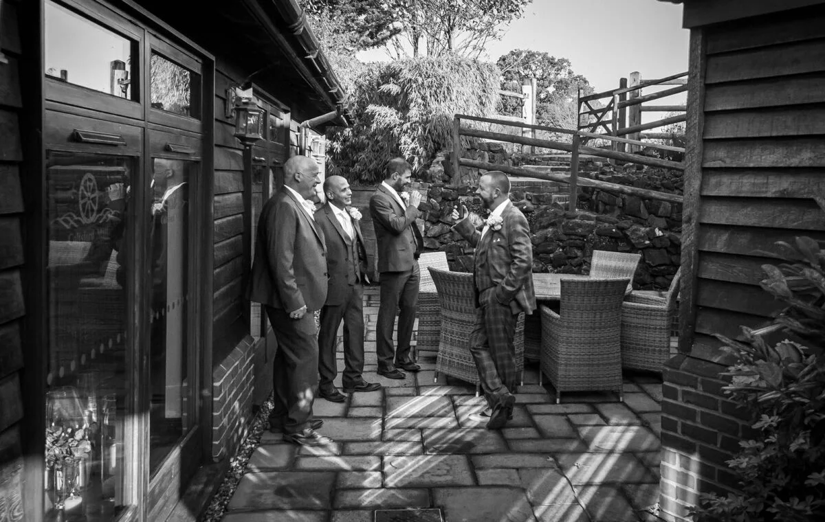 A black and white photo of a group of men standing in front of a house.