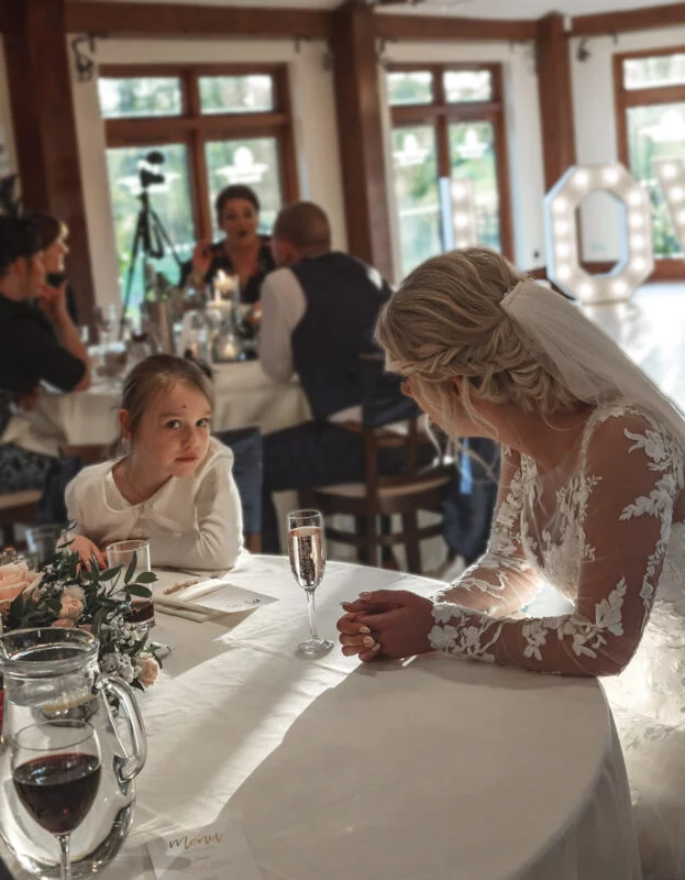 A bride and her daughter sitting at a table in a restaurant.
