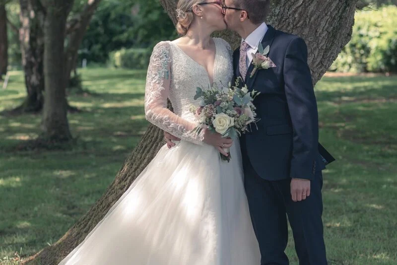 A bride and groom kissing under a tree.
