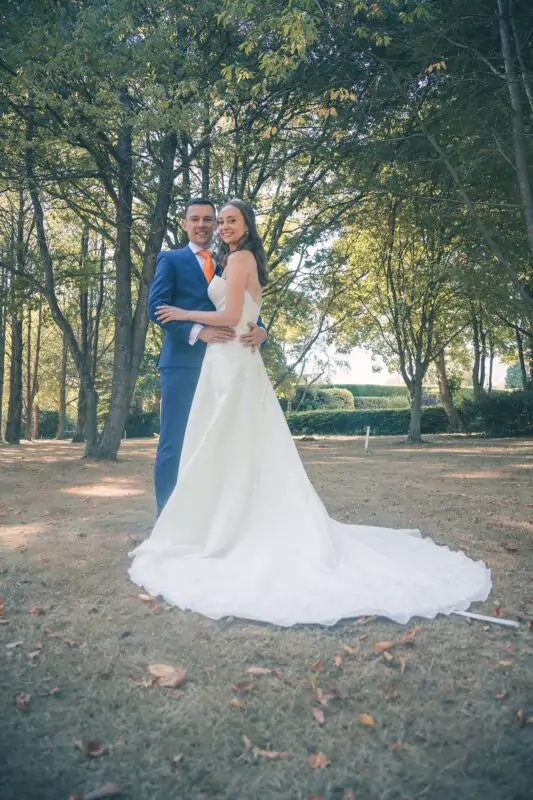 A bride and groom posing for a photo in the woods.