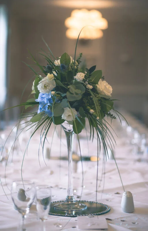 A table setting with blue and white flowers in a glass vase.