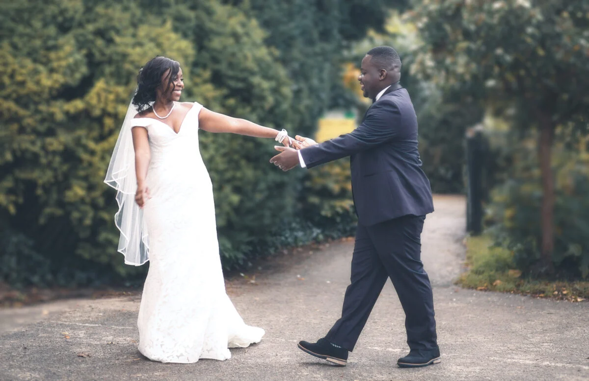 A bride and groom are walking down a path in a garden.