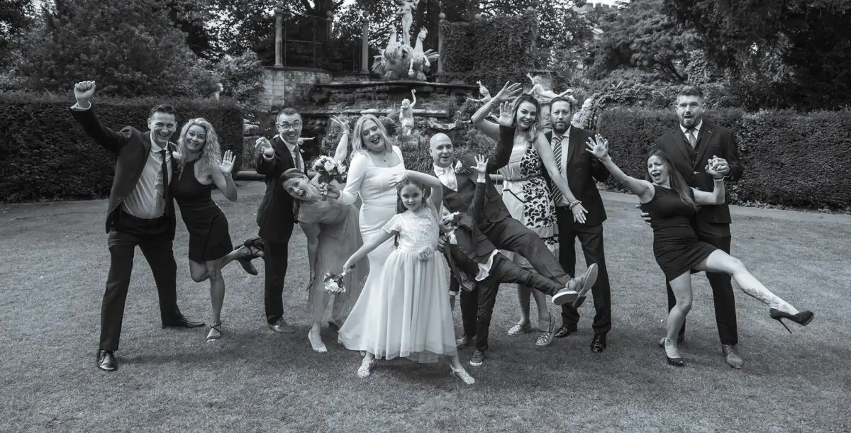 A black and white photo of a wedding party posing for a photo.