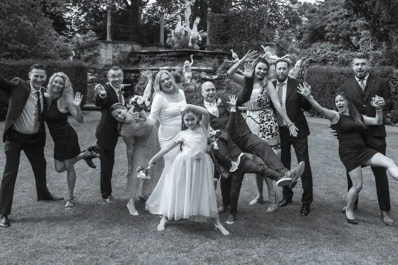 A black and white photo of a wedding party posing for a photo.