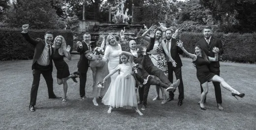 A black and white photo of a wedding party posing for a photo.