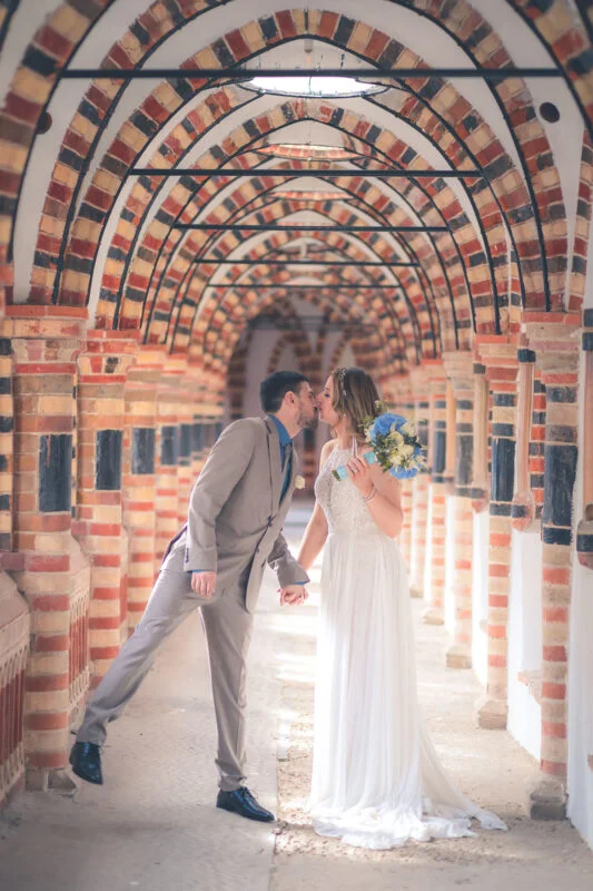 A bride and groom kissing under an archway.