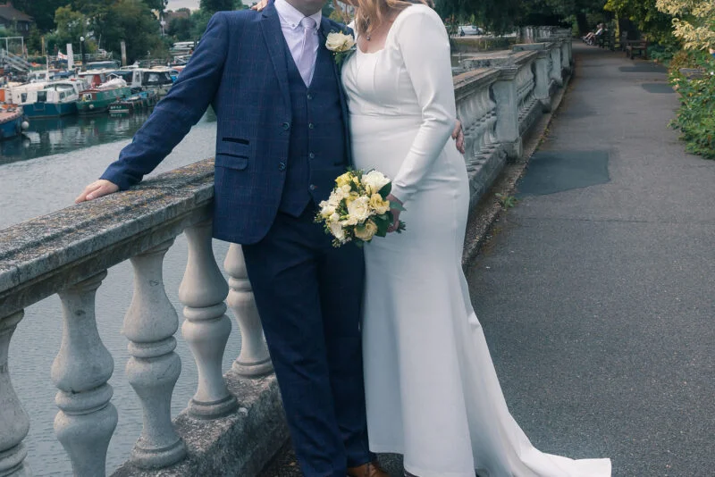A bride and groom posing on a bridge.