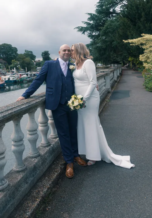 A bride and groom posing on a bridge.