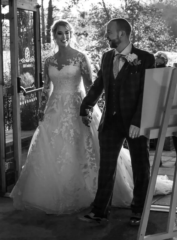 Black and white photo of a bride and groom walking down the aisle.