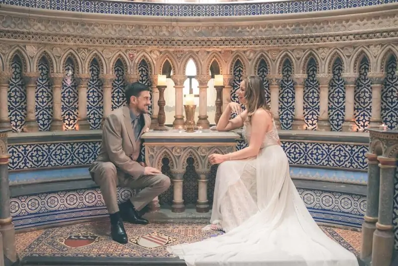 A bride and groom sitting on the steps of an ornate building.