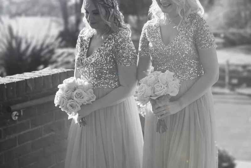 Two bridesmaids standing in front of a brick wall.