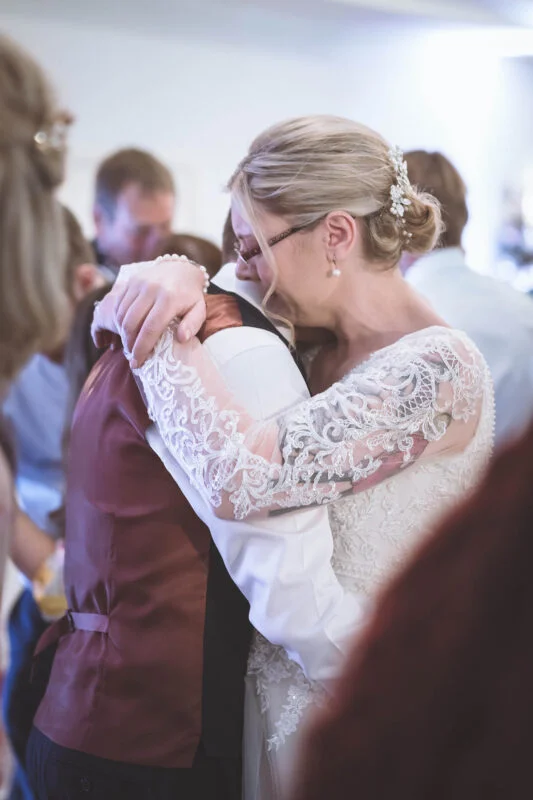 A bride and groom hugging at a wedding reception.