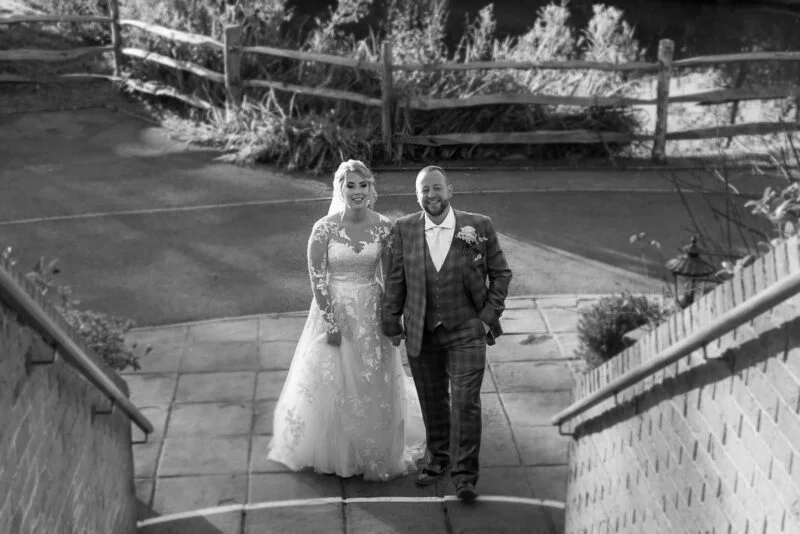 Black and white photo of a bride and groom walking down stairs.