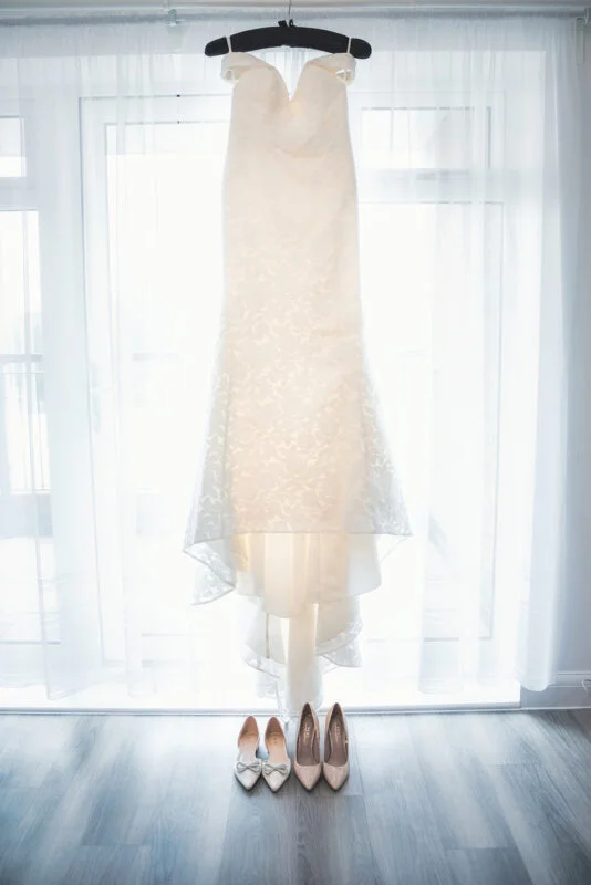 A wedding dress hanging in front of a window.
