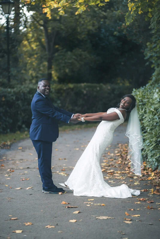 A bride and groom holding hands in a park.